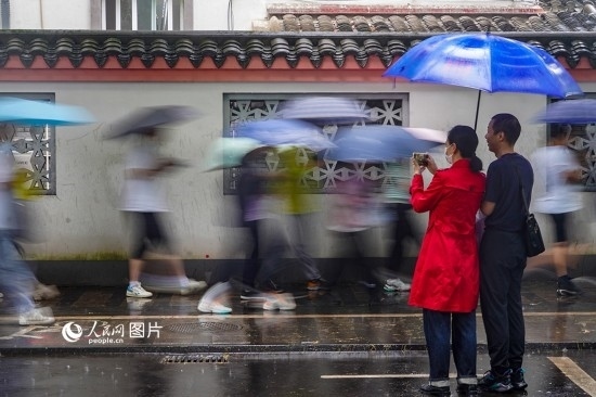 6月7日，在浙江省2023年普通高校招生考試鎮(zhèn)海中學考點，家長冒雨目送子女進入考場。人民網(wǎng) 章勇濤攝