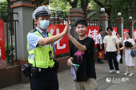 6月7日8時許，武漢中學考點門口，交警在維護秩序，并?？忌鸢耦}名。人民網(wǎng)記者 肖璐欣攝