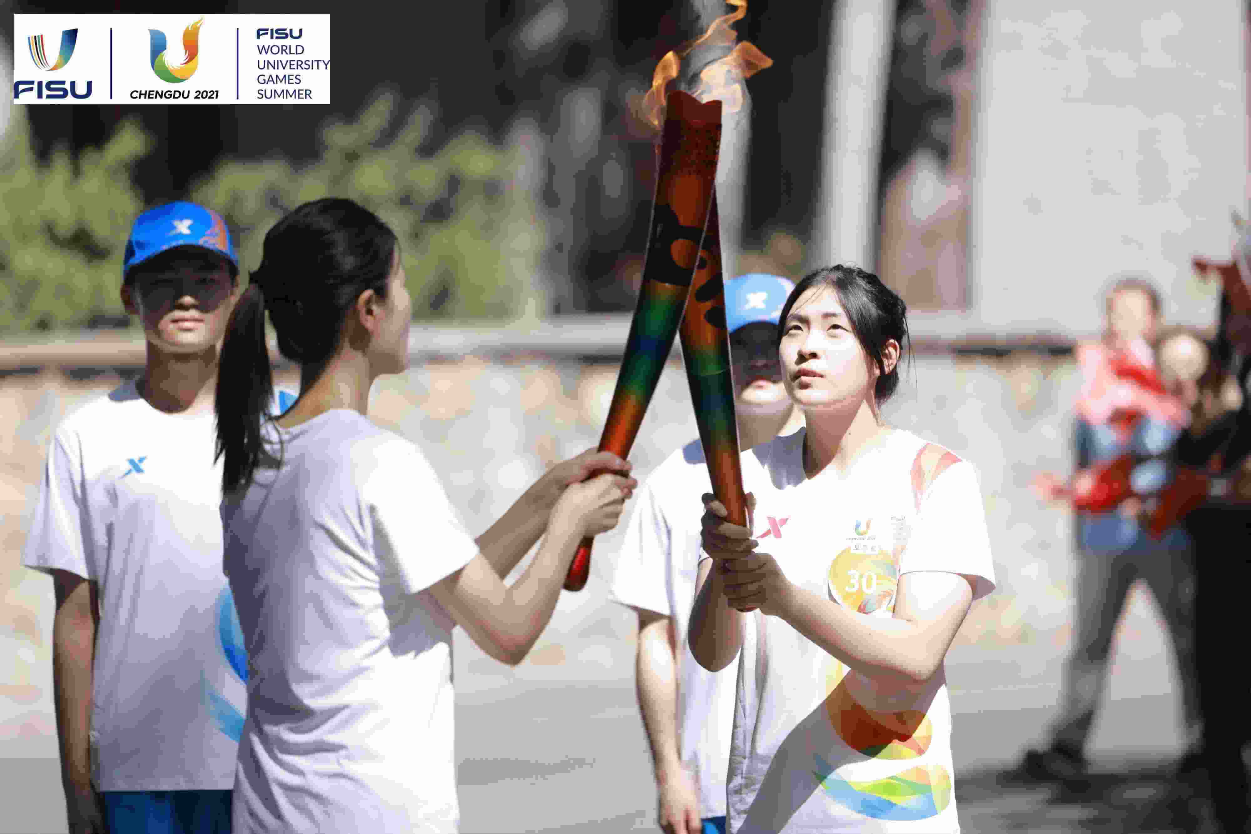 兩名大運會火炬手進(jìn)行火炬?zhèn)鬟f。 圖片來源：成都大運會執(zhí)委會供圖