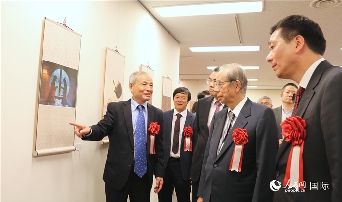 “湖州印象”攝影展主創(chuàng)、世界華人攝影協(xié)會副會長馮學敏向吳江浩大使、福田康夫前首相等嘉賓介紹展出作品。（人民網 許可攝）