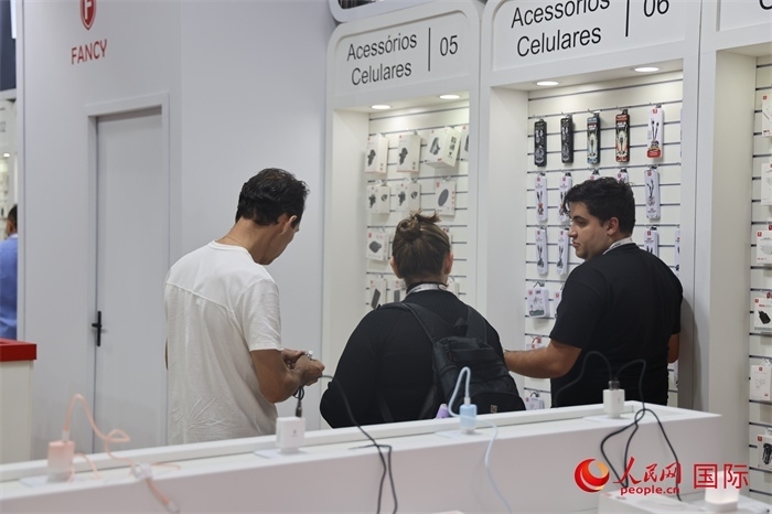 幾名參觀者在一個(gè)展臺(tái)前了解手機(jī)配件。（人民網(wǎng)記者 時(shí)元皓攝）