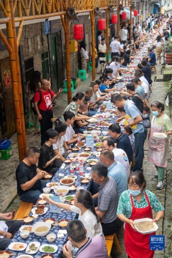 7月29日，在重慶市綦江區(qū)安穩(wěn)鎮(zhèn)，人們在“苗家伏羊節(jié)”上吃長桌宴。新華社記者 唐奕 攝