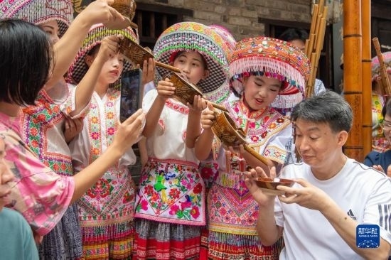 7月29日，在重慶市綦江區(qū)安穩(wěn)鎮(zhèn)，當(dāng)?shù)鼐用裨凇懊缂曳蚬?jié)”上用傳統(tǒng)習(xí)俗向游客表達(dá)祝福。新華社記者 唐奕 攝