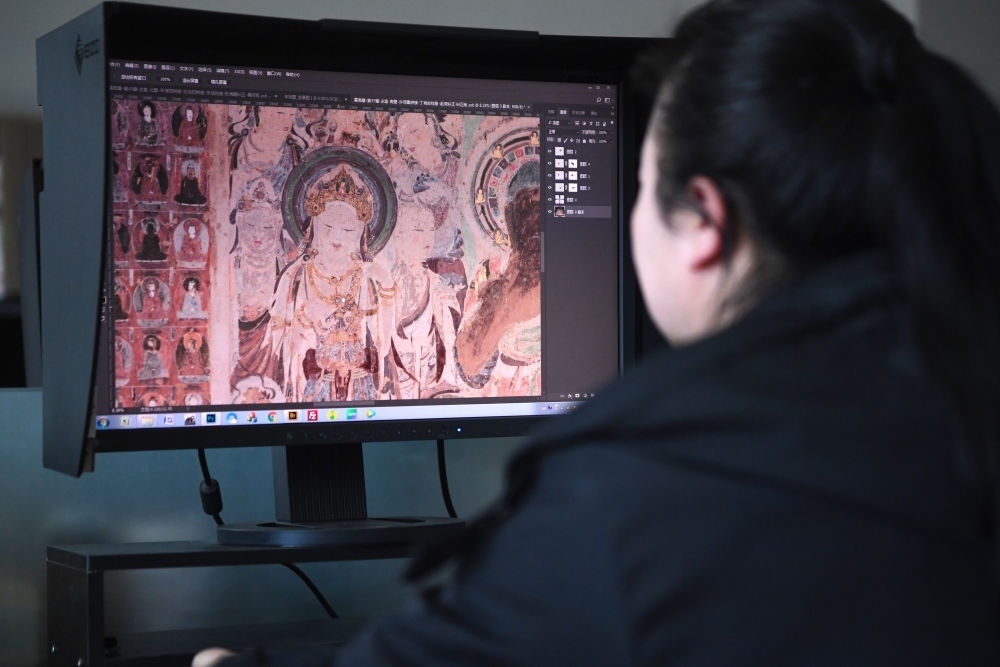敦煌研究院文物數(shù)字化保護(hù)團(tuán)隊(duì)圖像處理人員年海麗在拼接壁畫圖像（2023年4月25日攝）。數(shù)字化探索為莫高窟的保護(hù)與傳承開辟了全新路徑，數(shù)字技術(shù)讓敦煌文物走出洞窟，跨出國門，走向“永久保存、永續(xù)利用”。新華社記者 陳斌 攝