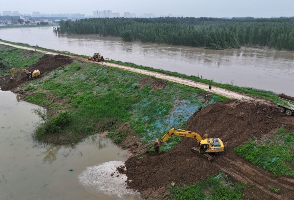 工人操作機械在白溝河左堤白溝新城高橋村段進行除險加固作業(yè)（8月4日攝，無人機照片）。新華社記者 朱旭東 攝