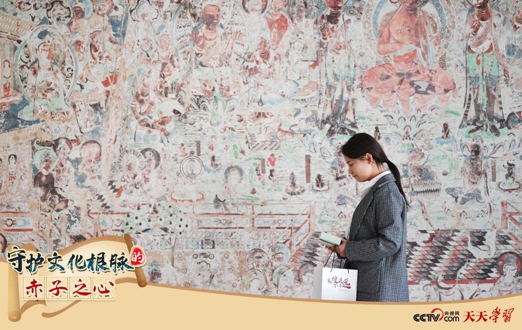 2023年4月25日，敦煌研究院文物數(shù)字化保護(hù)團(tuán)隊(duì)創(chuàng)意營(yíng)銷人員廖雪婷從一幅高保真復(fù)制壁畫前走過。