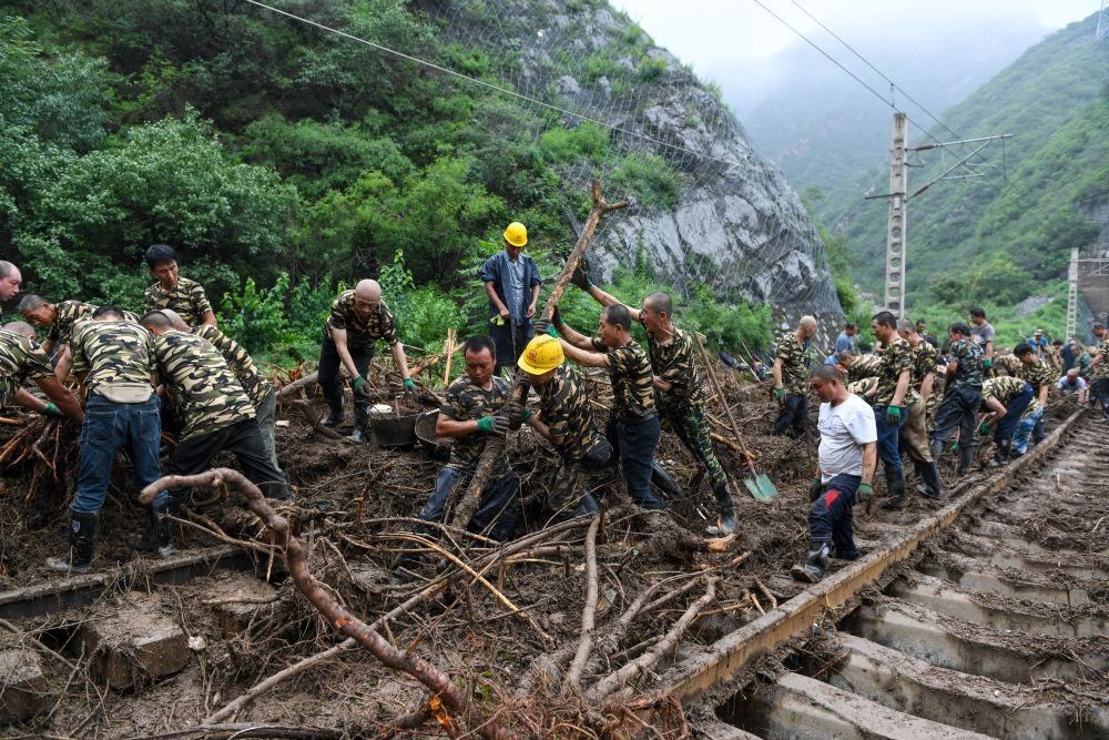 8月1日，在北京市門頭溝區(qū)水峪嘴村附近一段被阻斷的鐵路線上，中鐵六局工作人員在清理軌道上的雜物，全力恢復(fù)交通。新華社記者 鞠煥宗 攝