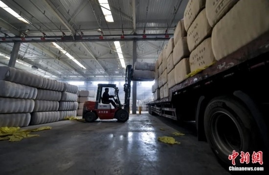 新疆喀什綜合保稅區(qū)，喀什啟路國際貿(mào)易有限公司的倉庫內(nèi)，工人正在裝載從塔吉克斯坦和烏茲別克斯坦進(jìn)口的棉花。劉新攝