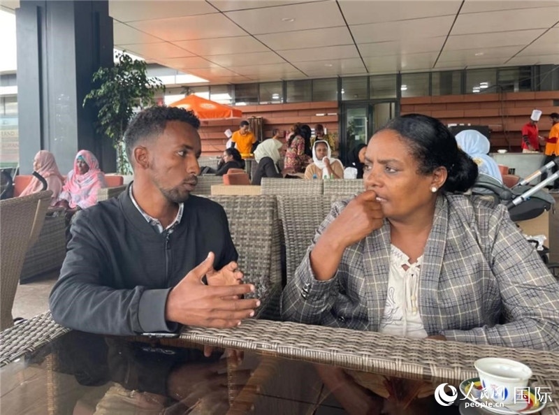 約漢斯（圖左）與德貝拉在友誼廣場咖啡廳交談。人民網(wǎng)記者 趙艷紅攝