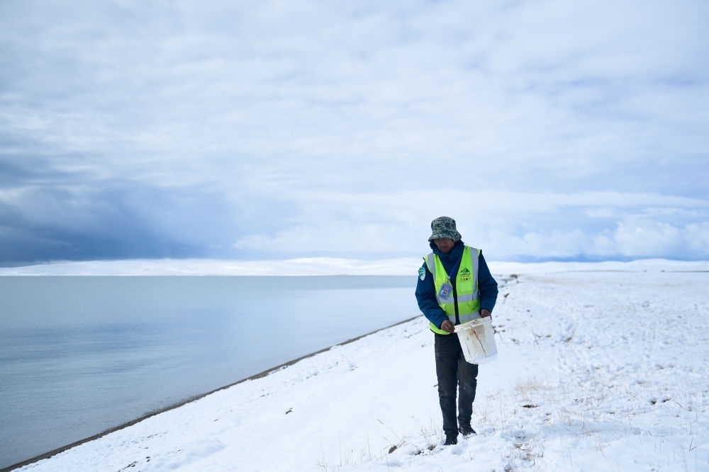 2021年10月20日，在青海省果洛藏族自治州瑪多縣扎陵湖鄉(xiāng)勒那村，三江源國(guó)家公園黃河源園區(qū)生態(tài)管護(hù)員在扎陵湖邊撿拾垃圾。新華社記者 張龍 攝