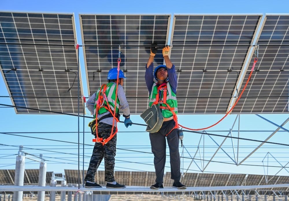 2023年7月22日，工人在位于內(nèi)蒙古杭錦旗庫(kù)布其沙漠億利生態(tài)示范區(qū)的蒙西基地庫(kù)布其200萬(wàn)千瓦光伏治沙項(xiàng)目工地安裝光伏板。新華社記者 劉磊 攝