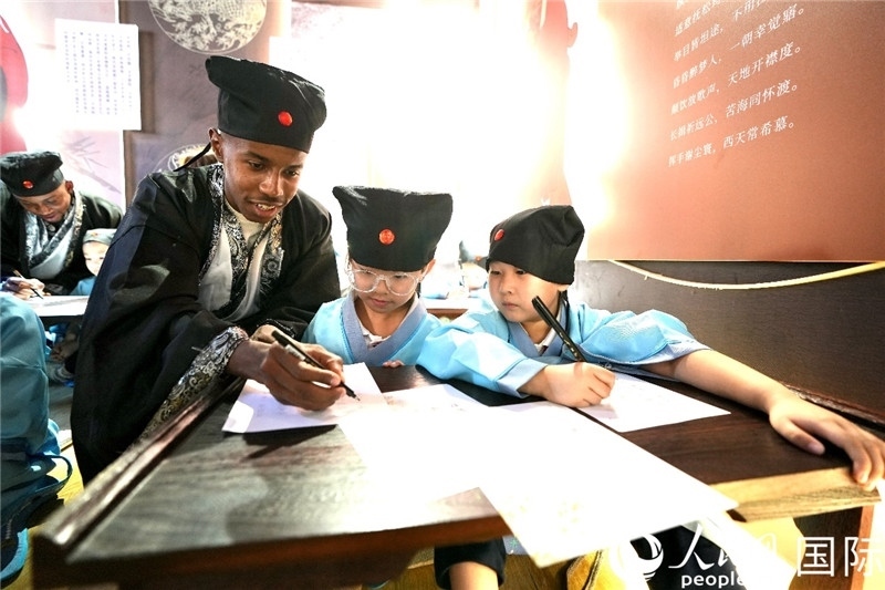 圖為選手與同學們一起寫書法。人民網(wǎng) 盧鵬宇攝