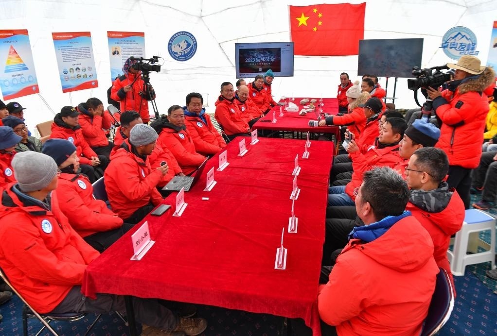 海拔4950米的卓奧友峰科考大本營，科考隊員趙華標(biāo)（手拿麥克風(fēng)看電腦者）在宣讀剛剛接收到的頂峰氣象觀測數(shù)據(jù)，這標(biāo)志著峰頂自動氣象站架設(shè)成功，成功傳回觀測數(shù)據(jù)（10月1日攝）。新華社記者晉美多吉 攝