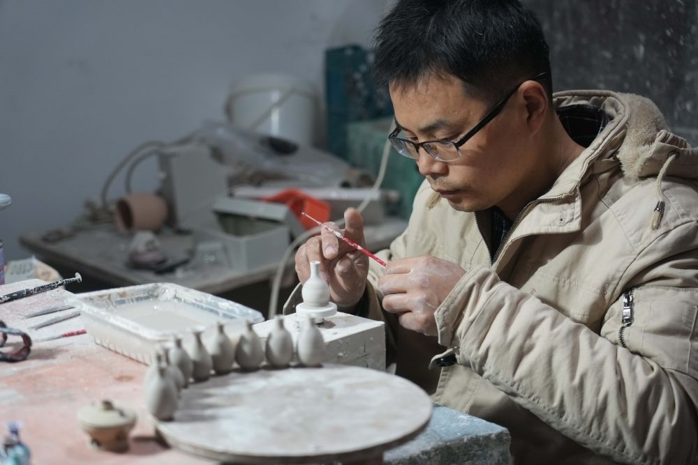↑2021年12月15日，來(lái)自安徽的王文化在制作微型陶瓷作品，他來(lái)景德鎮(zhèn)已有十多年時(shí)間。