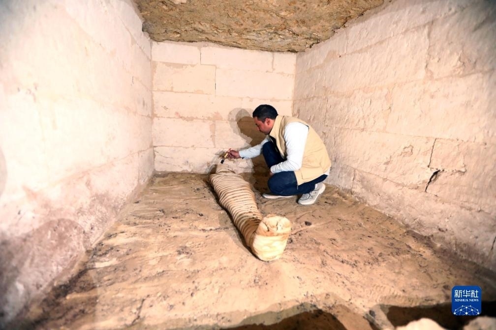 10月15日，在埃及明亞省考古現(xiàn)場，考古人員清理一座石鑿墓中的木乃伊。新華社發(fā)（艾哈邁德·戈馬攝）