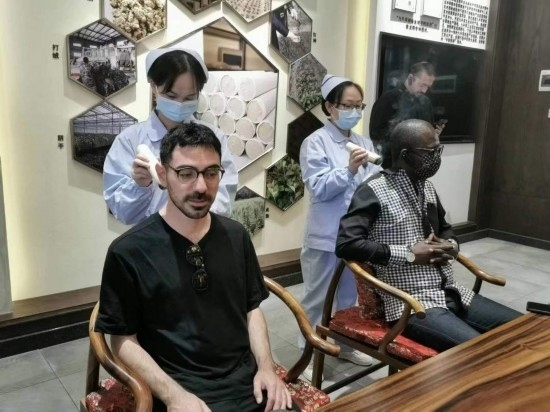 2023“一帶一路”媒體合作論壇聯(lián)合采訪團團員在九牛草展示館體驗艾灸。（本報記者 黃超攝）