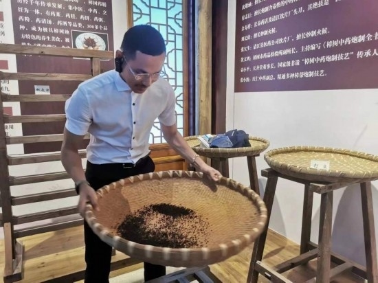 2023“一帶一路”媒體合作論壇聯(lián)合采訪團團員在非遺文化展示館體驗中藥炮制技藝。（本報記者 黃超攝）