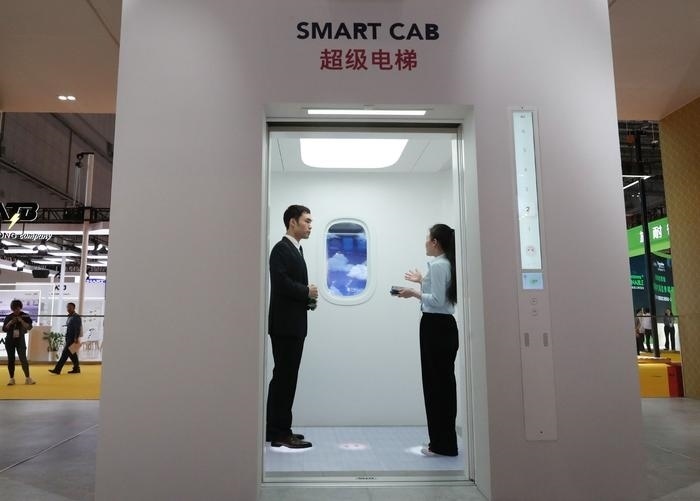 11月5日，工作人員（右）在第六屆進(jìn)博會上向參觀者介紹奧的斯公司全新推出的超級電梯。