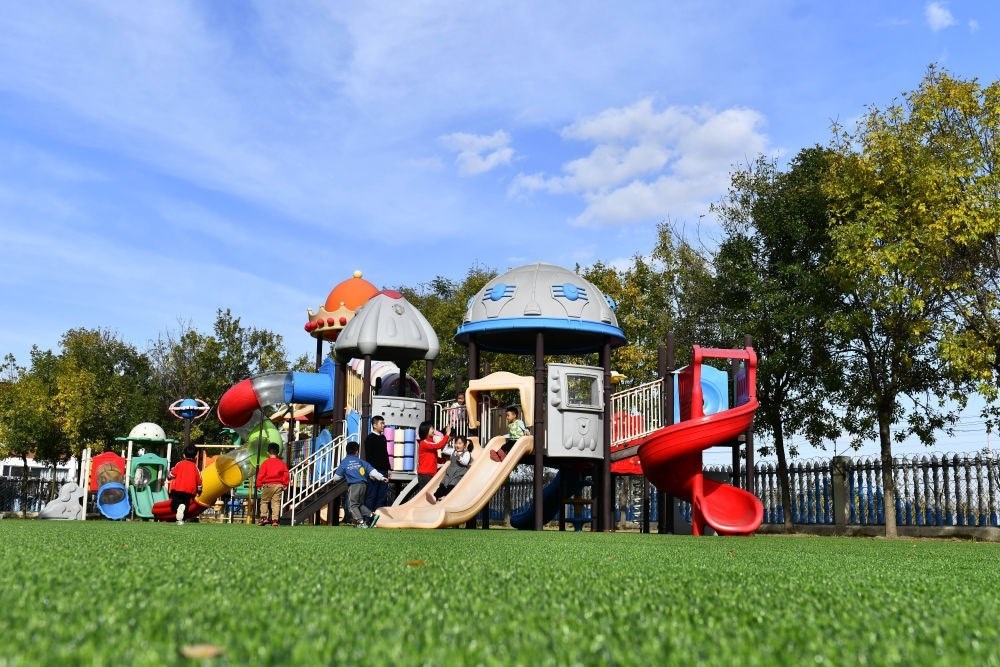 在山東省東營市墾利區(qū)楊廟社區(qū)幼兒園，孩子們在老師的帶領(lǐng)下進行戶外活動（2021年10月19日攝）。新華社記者 郭緒雷 攝