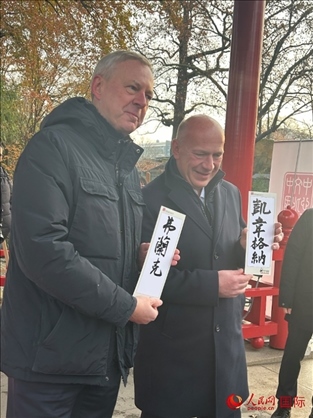 柏林市長韋格納（右）、動物園監(jiān)事會主席布魯克曼（左）手持中國文化中心工作人員現(xiàn)場手書的中文名字。人民網(wǎng)記者 徐馨攝