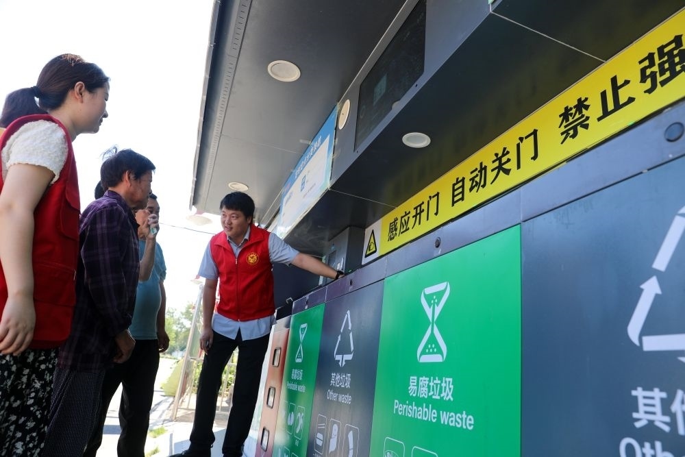 在安徽省合肥市長豐縣莊墓鎮(zhèn)棗林社區(qū)，志愿者指導(dǎo)居民使用智能垃圾分類回收設(shè)備（2023年9月1日攝）。新華社記者 曹力 攝