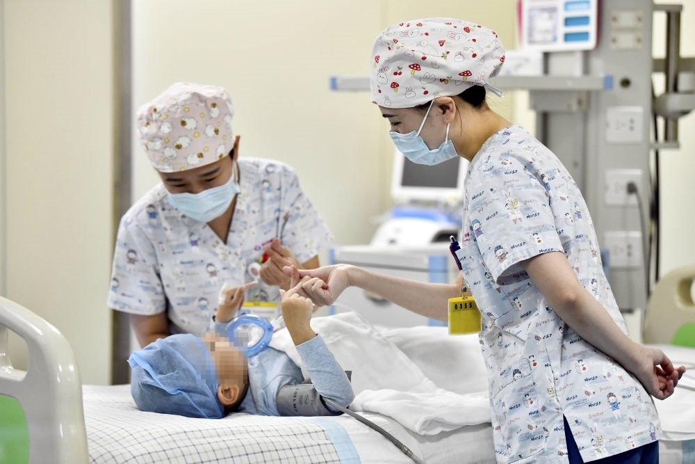 在山東省棗莊市婦幼保健院兒童ICU病房，醫(yī)護(hù)人員為完成靶向治療藥物諾西那生鈉的4歲脊髓性肌萎縮癥患兒加油鼓勁（2022年1月1日攝）。諾西那生鈉注射液是我國首個獲批治療脊髓性肌萎縮癥的進(jìn)口藥物，2019年進(jìn)入中國市場時，每針價格近70萬元。在2021年國家醫(yī)保目錄藥品談判中，以3.3萬元每針的價格進(jìn)入新版醫(yī)保藥品目錄。新華社記者 郭緒雷 攝