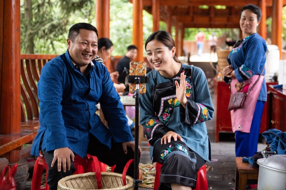 在湖南省湘西土家族苗族自治州花垣縣十八洞村，十八洞村扶貧隊(duì)長麻輝煌（左）與返鄉(xiāng)大學(xué)生施林嬌（中）一起直播推銷土特產(chǎn)（2020年5月15日攝）。新華社記者 陳思汗 攝