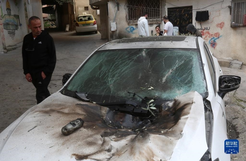 12月17日，在約旦河西岸城市圖勒凱爾姆附近的一處難民營，人們查看在沖突中損毀的車輛。新華社發(fā)（尼達(dá)爾·艾仕塔耶?dāng)z）