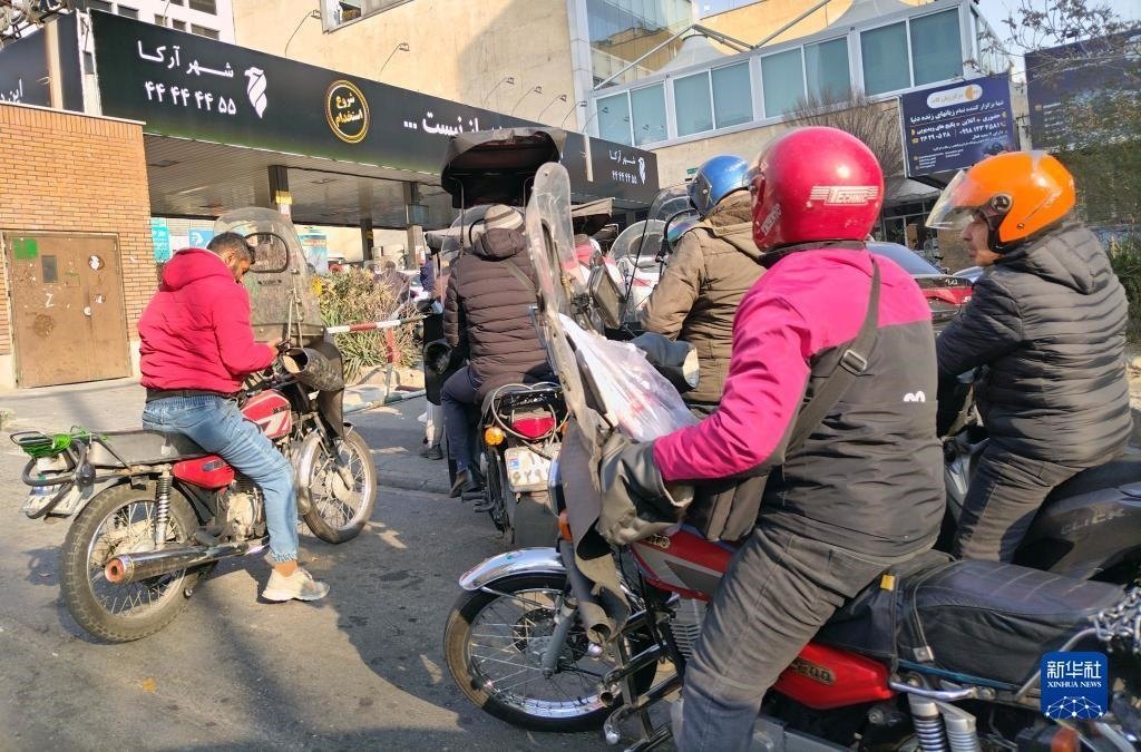 12月18日，摩托車在伊朗首都德黑蘭的一家加油站外等待加油。新華社記者 沙達提 攝