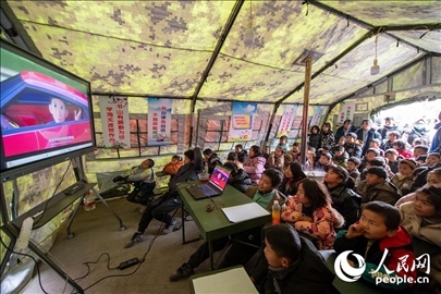 12月22日，在積石山縣大河家鎮(zhèn)大河村安置點，陸軍76集團軍某旅搭建的“臨時學?！眱?nèi)，小朋友正在看動畫片。人民網(wǎng)記者 翁奇羽攝