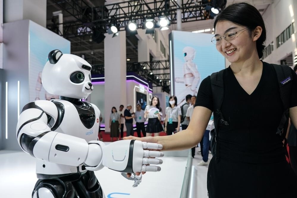 2023年8月16日，一名女士在北京舉辦的2023世界機(jī)器人大會(huì)現(xiàn)場與智能機(jī)器人握手。新華社記者彭子洋攝