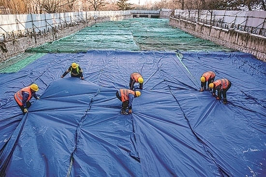 1月3日，房山區(qū)東風(fēng)街道，工人正在修復(fù)的河道內(nèi)給混凝土鋪設(shè)保溫布。