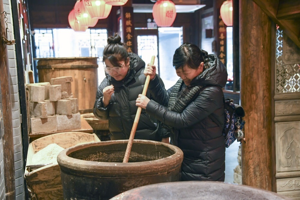 游客在平遙古城東湖老醋坊內(nèi)體驗(yàn)陳醋發(fā)酵打耙（2022年1月28日攝）。新華社發(fā)（梁生仁攝）