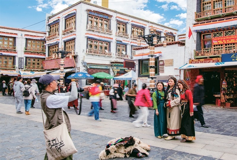 千年八廓街，見證民族團結。2021年7月，習近平總書記來到位于西藏拉薩老城區(qū)的八廓街，感慨地說：“千年八廓街，是我們各民族建起來的八廓街。各民族文化在這里交流交往交融，我們中華民族的大家庭在這里其樂融融?！眻D為2023年6月13日，游客身著藏裝在八廓街拍照留念。 新華社記者 姜帆/攝