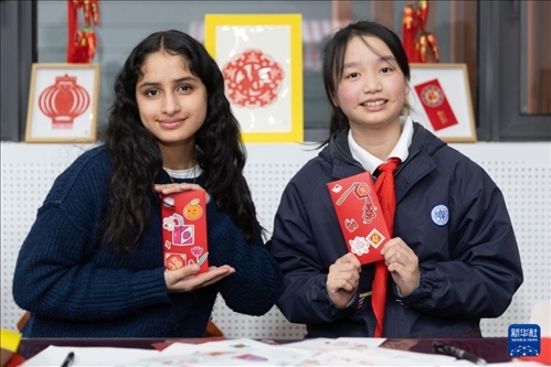 1月28日，美國馬斯卡廷中學學生（左）和復旦大學第二附屬學校學生展示互相送出的寫有寄語祝福的紅包。 新華社記者 王翔 攝