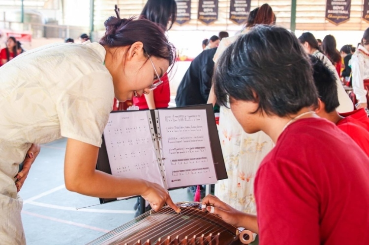 志愿者教師指導(dǎo)學(xué)生彈奏古箏?；顒又鬓k方供圖