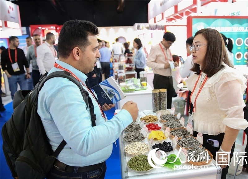 圖為一家中國(guó)干果參展企業(yè)代表與采購商洽談。人民網(wǎng) 塔里克·易卜拉欣攝