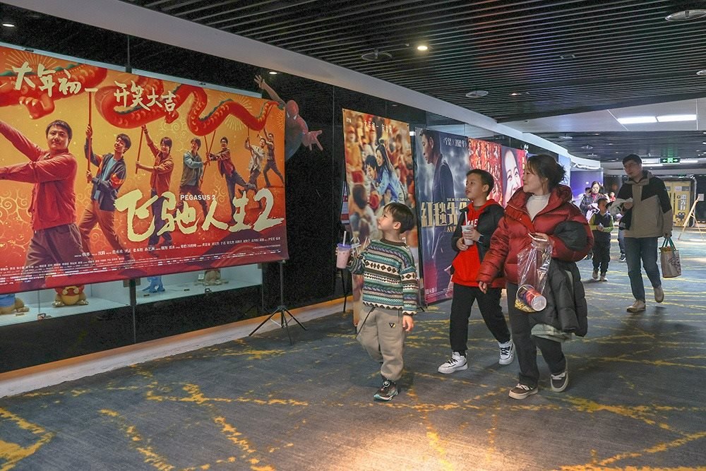 △ 2024年2月16日，在江西贛州一家電影院，觀眾從春節(jié)檔電影的宣傳展板前走過。