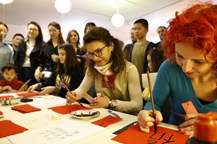 羅馬尼亞觀眾學(xué)習(xí)用毛筆寫(xiě)“?！弊?。中國(guó)文化中心供圖