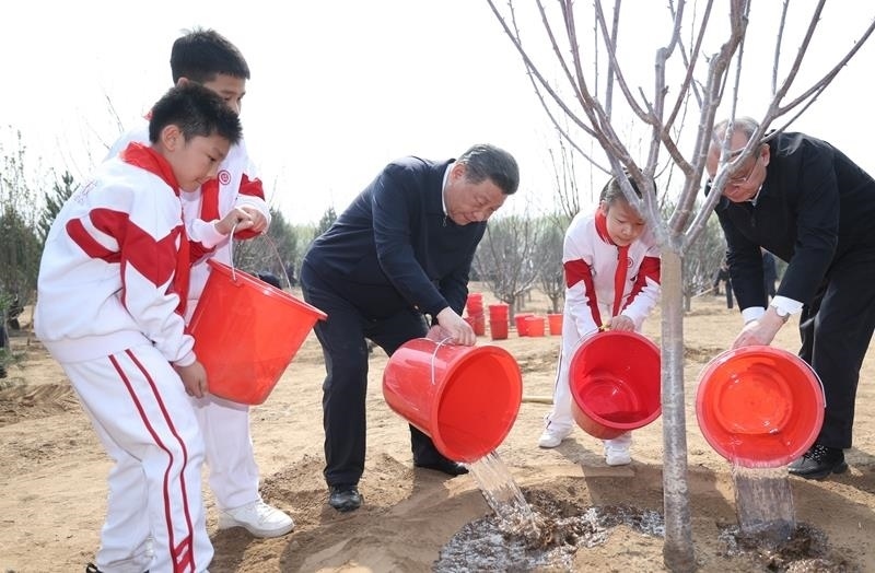 2024年4月3日，習(xí)近平總書記同少先隊(duì)員一起給剛栽下的樹苗澆水。