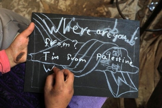 2023年12月28日，一名學(xué)生在加沙地帶南部城市拉法一所學(xué)校的臨時(shí)教室中寫下“我來自巴勒斯坦”的字樣。新華社發(fā)（里澤克·阿卜杜勒賈瓦德攝）