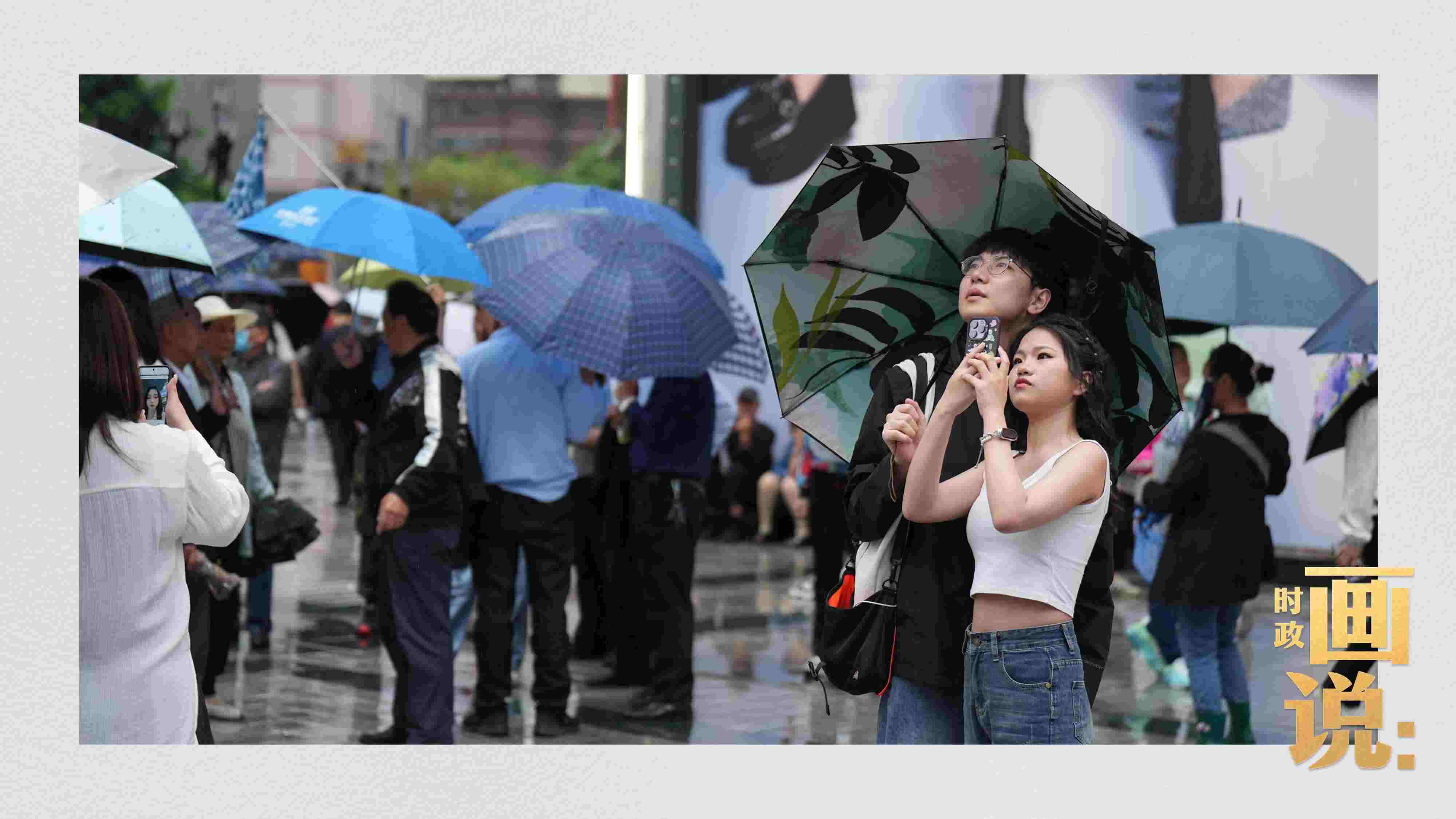 △細雨中的解放碑步行街，騎在父親肩膀的小女孩好奇張望。