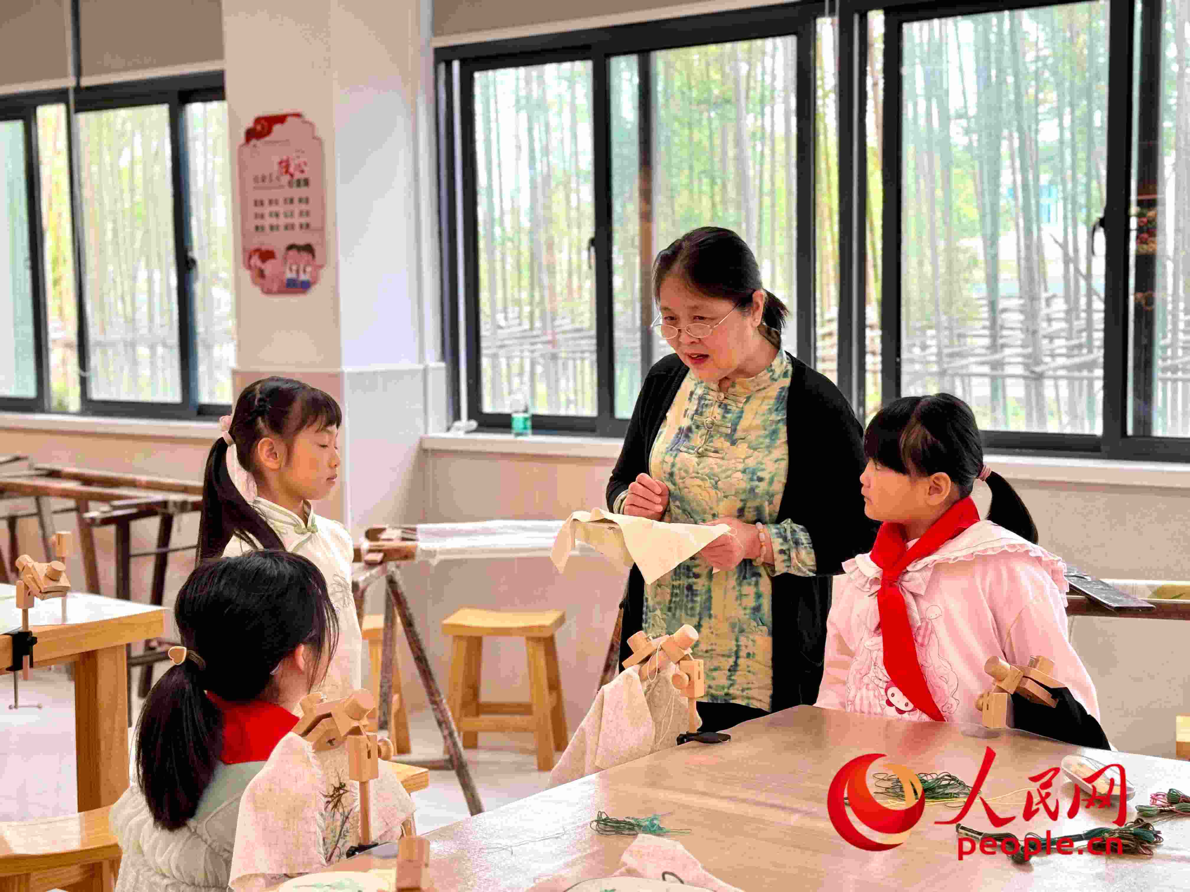 顧建珍（左三）在教孩子們刺繡知識(shí)。人民網(wǎng) 周靜圓攝