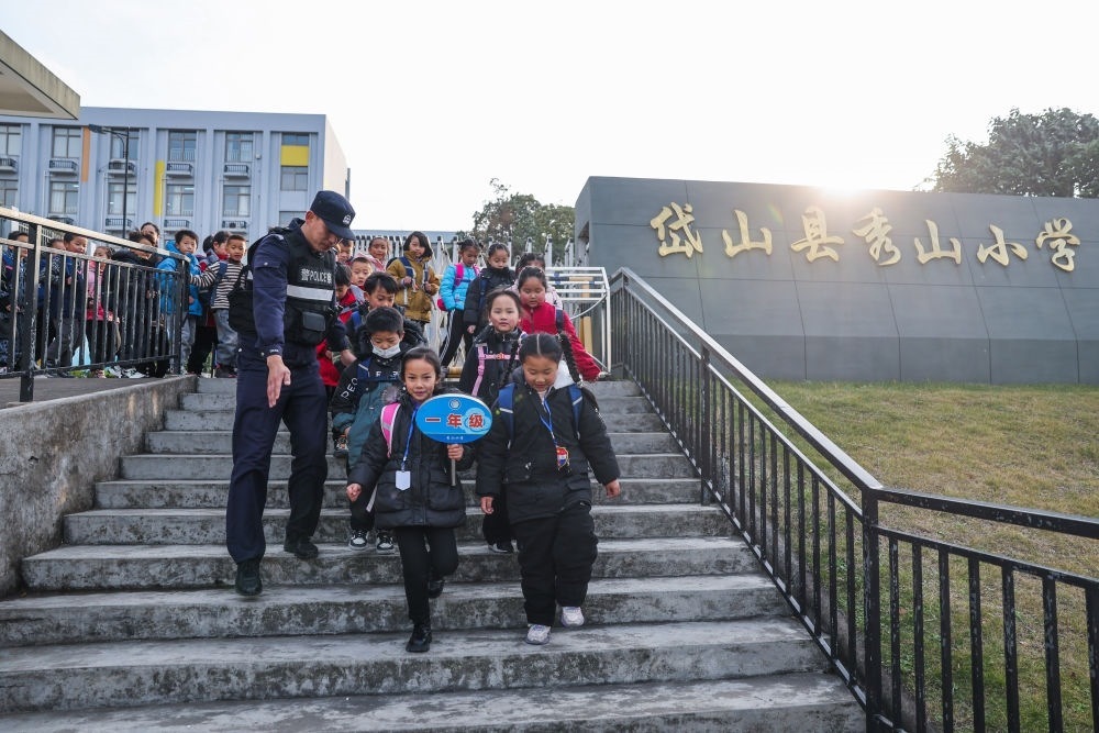 2023年12月20日，秀山派出所民警在秀山小學(xué)放學(xué)時(shí)間參與“護(hù)學(xué)崗”維持秩序，同時(shí)接獨(dú)自放學(xué)的學(xué)生去“民生小鋪”。浙江省舟山市岱山縣公安局秀山派出所聯(lián)合鄉(xiāng)鎮(zhèn)、社區(qū)成立“民生小鋪”，為當(dāng)?shù)鼐用?、外來?wù)工人員及其子女等服務(wù)，協(xié)助解決外來務(wù)工人員在工作、生活等方面的矛盾和問題，助力鄉(xiāng)鎮(zhèn)基層治理。新華社記者 徐昱 攝
