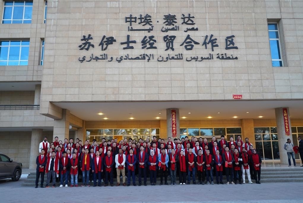 2024年2月11日，在位于埃及蘇伊士省的中?！ぬ┻_(dá)蘇伊士經(jīng)貿(mào)合作區(qū)，中埃員工在合作區(qū)辦公大樓前合影拜年。新華社發(fā)（泰達(dá)合作區(qū)供圖）