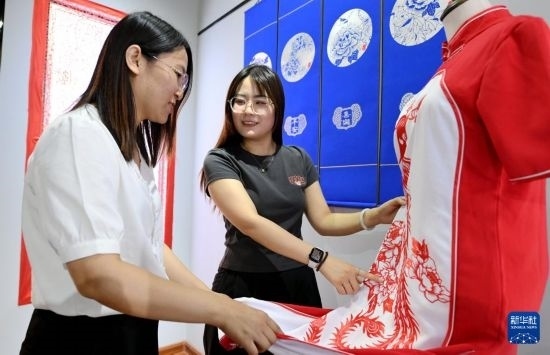 5月31日，在衡水市阜城縣一家剪紙工作室，游客在觀賞帶有剪紙?jiān)氐钠炫邸? width=