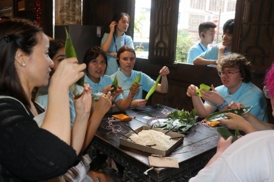 6月9日，美國(guó)青年代表在重慶永川松溉古鎮(zhèn)體驗(yàn)包粽子。新華社記者 周思宇 攝