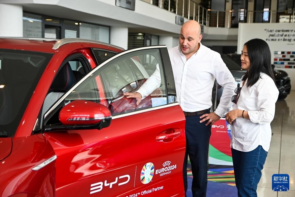 2024年5月29日，在馬耳他比爾基卡拉，馬耳他哈桑-扎米特汽車公司首席執(zhí)行官德古阿拉（左）介紹一輛比亞迪純電動汽車。新華社發(fā)（喬納森·博格 攝）