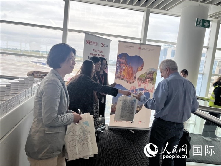 圖為工作人員向乘客發(fā)放復(fù)航首班禮物。 牛瑞飛攝