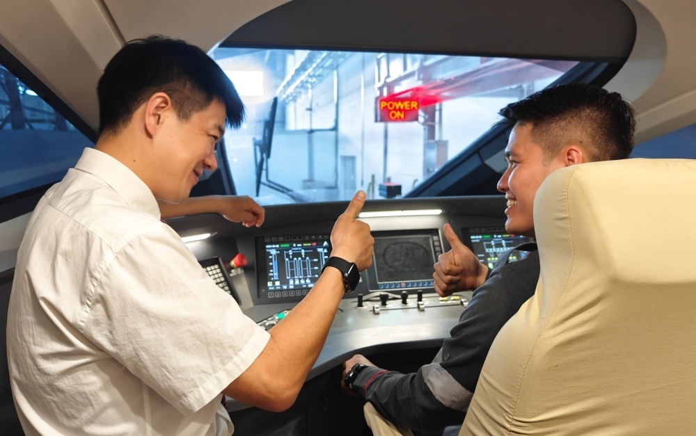 2023年8月25日，在印度尼西亞萬隆的雅萬高鐵德卡魯爾動車所內(nèi)，中國師傅穆振（左）向印尼火車司機(jī)塞蒂亞萬講解動車組出庫前的上電作業(yè)。新華社記者 徐欽 攝